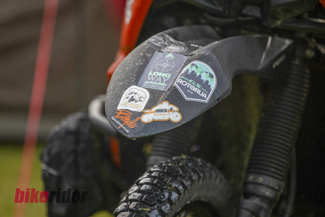 Mixed adventure motorcycles parked at Kai Iwi Beach Holiday Park during BMW GS Rallye, BOYD motorcycle sticker