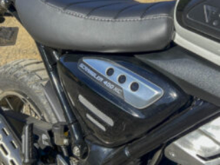 Triumph Scrambler 400XC side panel parked on gravel