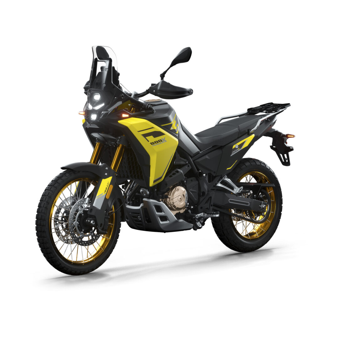 Yellow and black adventure motorcycle seen from the front-left, with windshield and rugged off-road tires