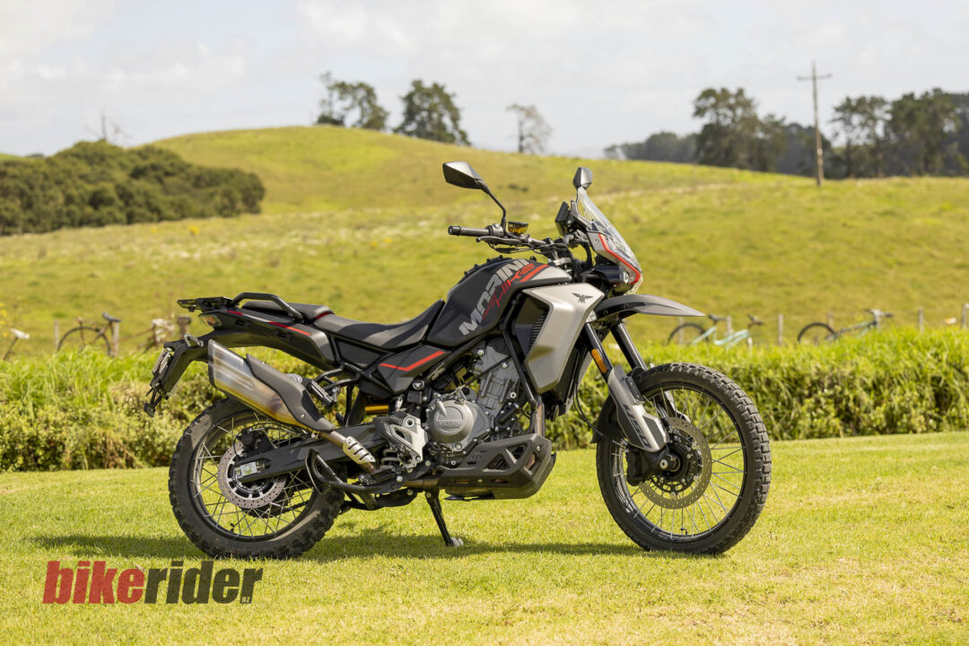 Adventure motorcycle parked on a grassy field with rolling hills in the background and a clear sky