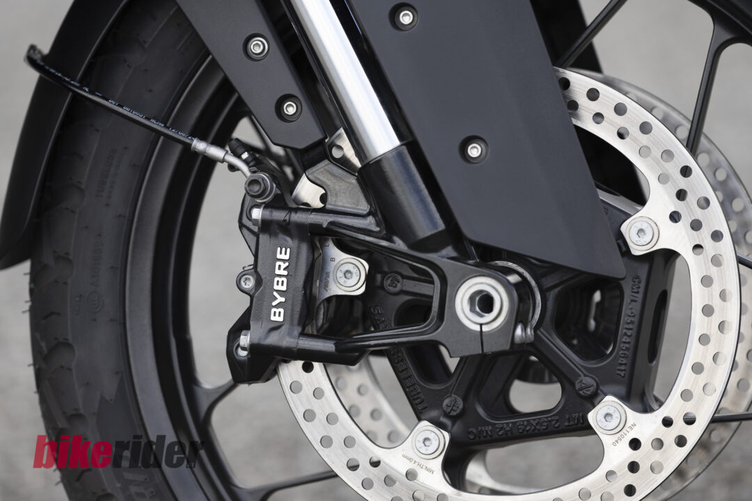 20260703-Norton_Atlas_2026_Details1-1080x720 Close-up of a motorcycle front brake disc and caliper (BYBRE) with braided brake line and tire in the background