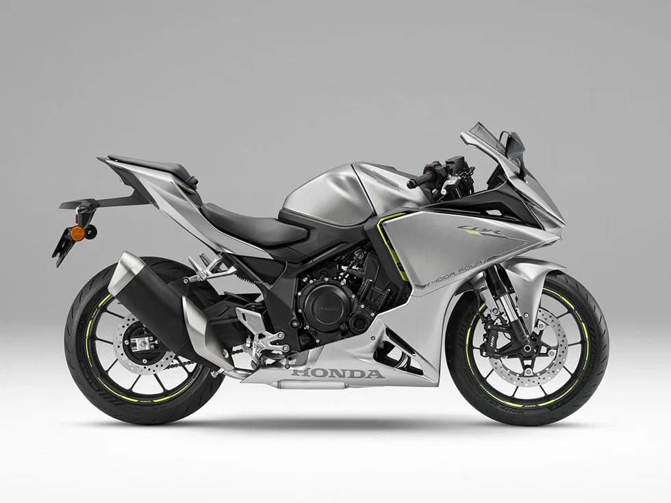 Side profile of a silver Honda sport motorcycle with neon yellow-green accents, black frame, and visible exhaust on a neutral background.