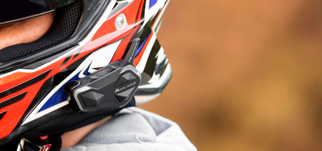 Close-up of a colorful motocross helmet with a Midland chin guard and orange background image blur