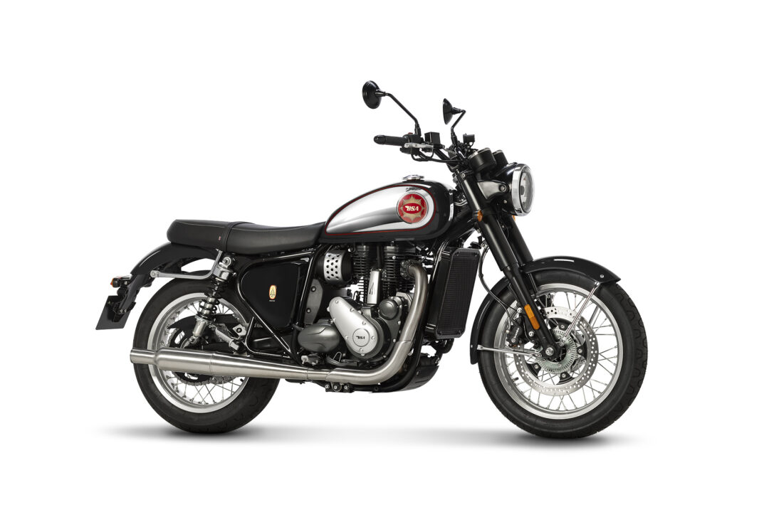 Black classic motorcycle shown in a left-front side view with chrome exhaust and a red emblem on the fuel tank on a white background, high detail.