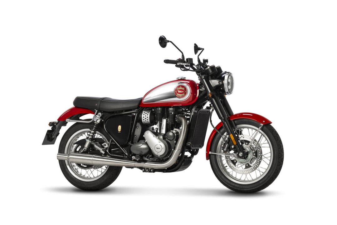 Red classic motorcycle shown from the left side with a chrome exhaust and round headlight on a white background.
