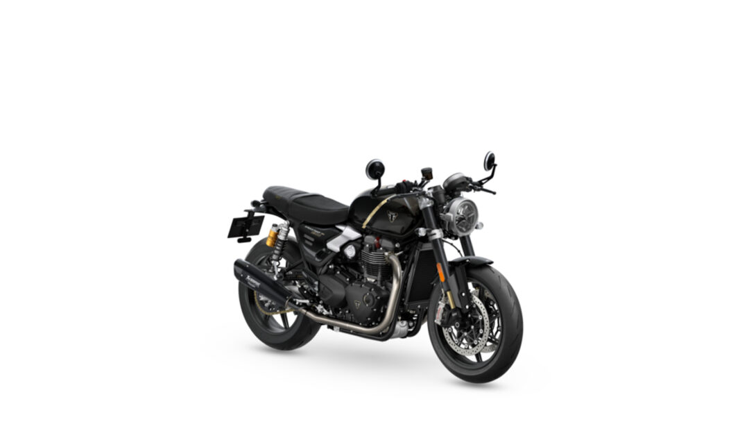 Black Triumph motorcycle photographed from the front-left, showing a round headlamp and exposed engine on a white background.
