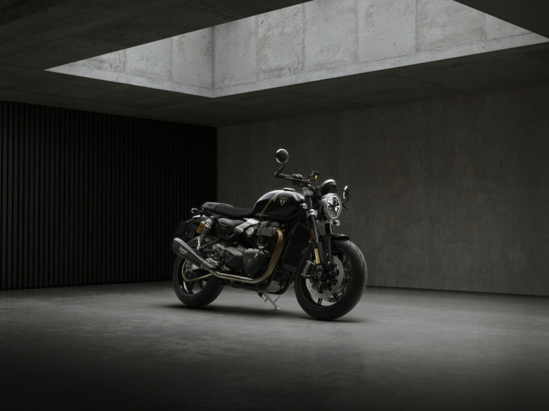 Black motorcycle parked in a dim concrete space with dramatic overhead light.