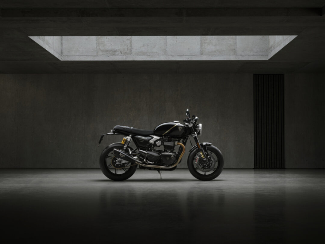 Black motorcycle parked in a dark concrete parking area beneath a rectangular skylight shape in the ceiling.