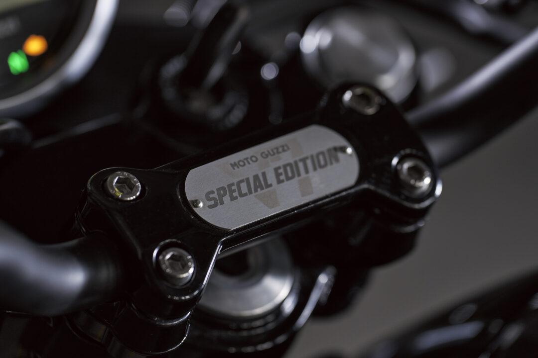 Close-up of a Moto Guzzi Special Edition badge on a black motorcycle frame to convey branding and edition status.