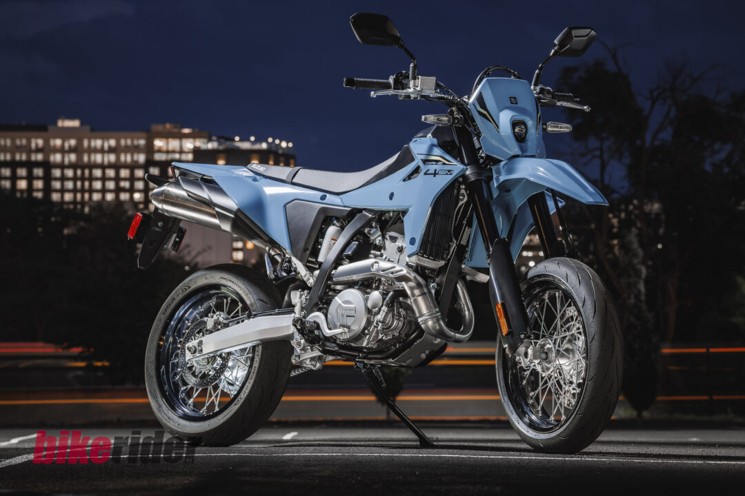 Blue sport motorcycle parked on a dark city street at night with blurred city lights in the background, showcasing its blue body panels and chrome engine.