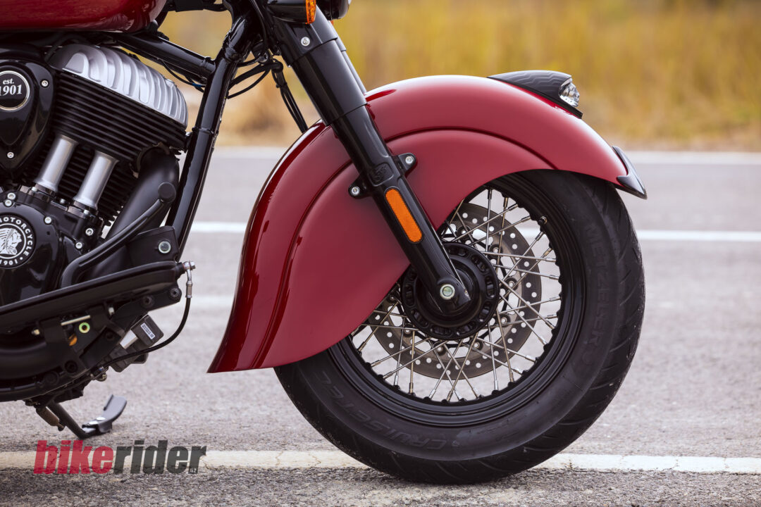 Close-up of a red motorcycle front fender and front wheel, with visible engine fins and black frame detailing