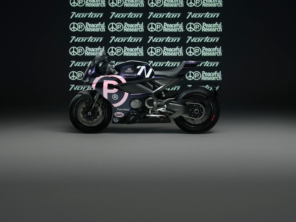 Side view of a black and pink Norton sport motorcycle in a studio with a branded backdrop.