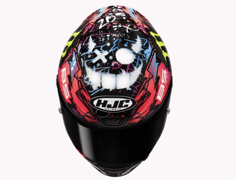 Full-face motorcycle helmet with a black visor and a vibrant skull graffiti design featuring pink, blue, and yellow accents, and the HJC logo on the front.