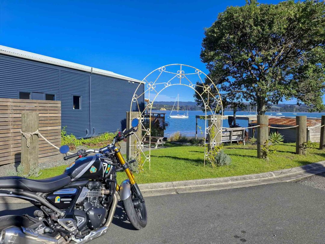 Triumph 400X NZ parked outside cafe by water