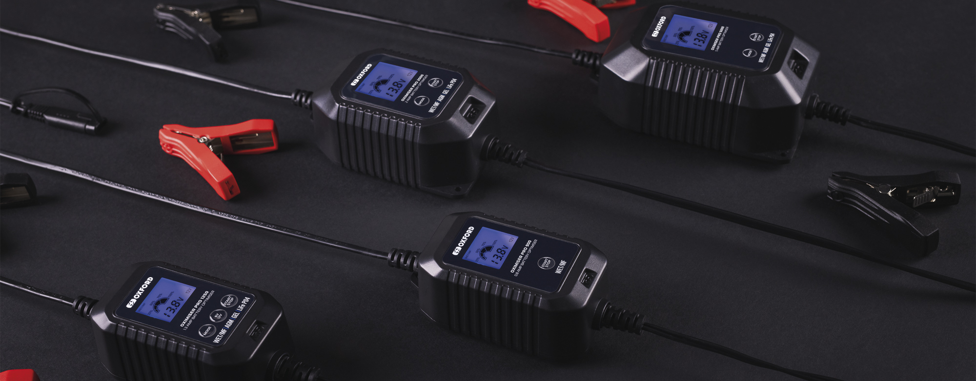 Four Oxford Oximiser Pro battery chargers with LCD displays and clamps