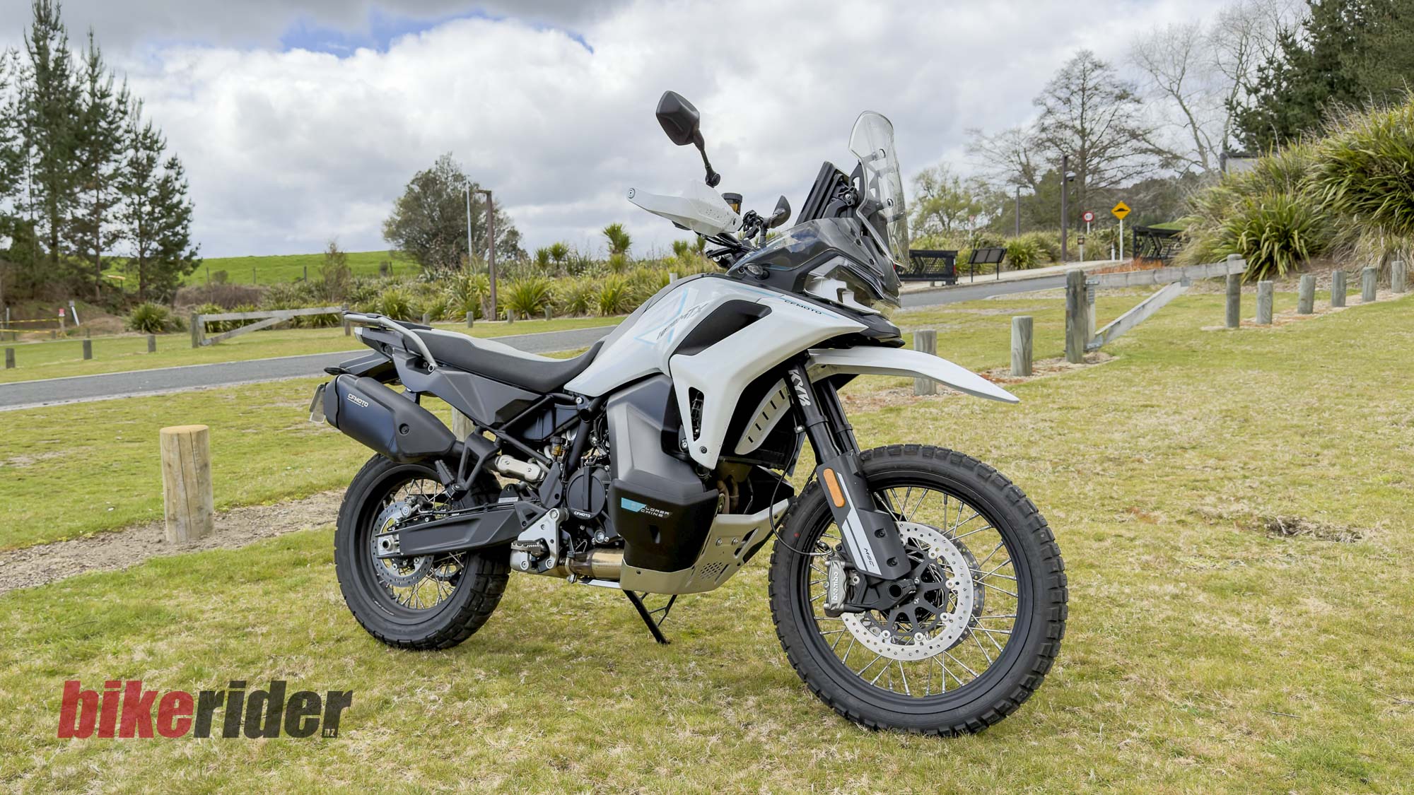 White CFMOTO 1000MT-X adventure bike parked on grass, viewed from the front right