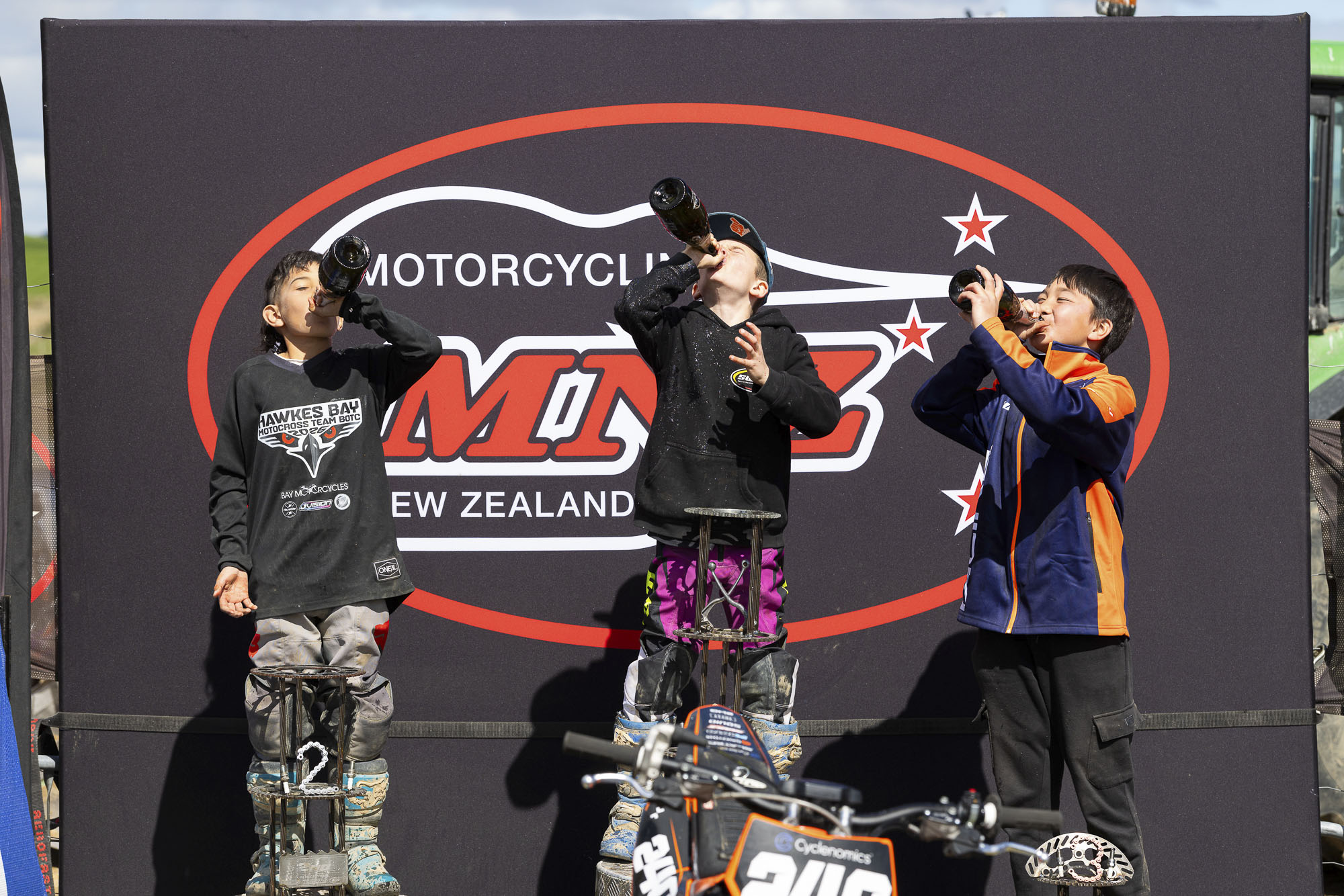 20261004-20261004_MiniMX_3589 The MX65 9-11 Years class podium celebrates with champagne (sparkling grape juice), from left: Dante McConnell (2nd), Royce Bush (1st) and Anand Rothe (3rd) at the 2026 NZ Mini Motocross Nationals