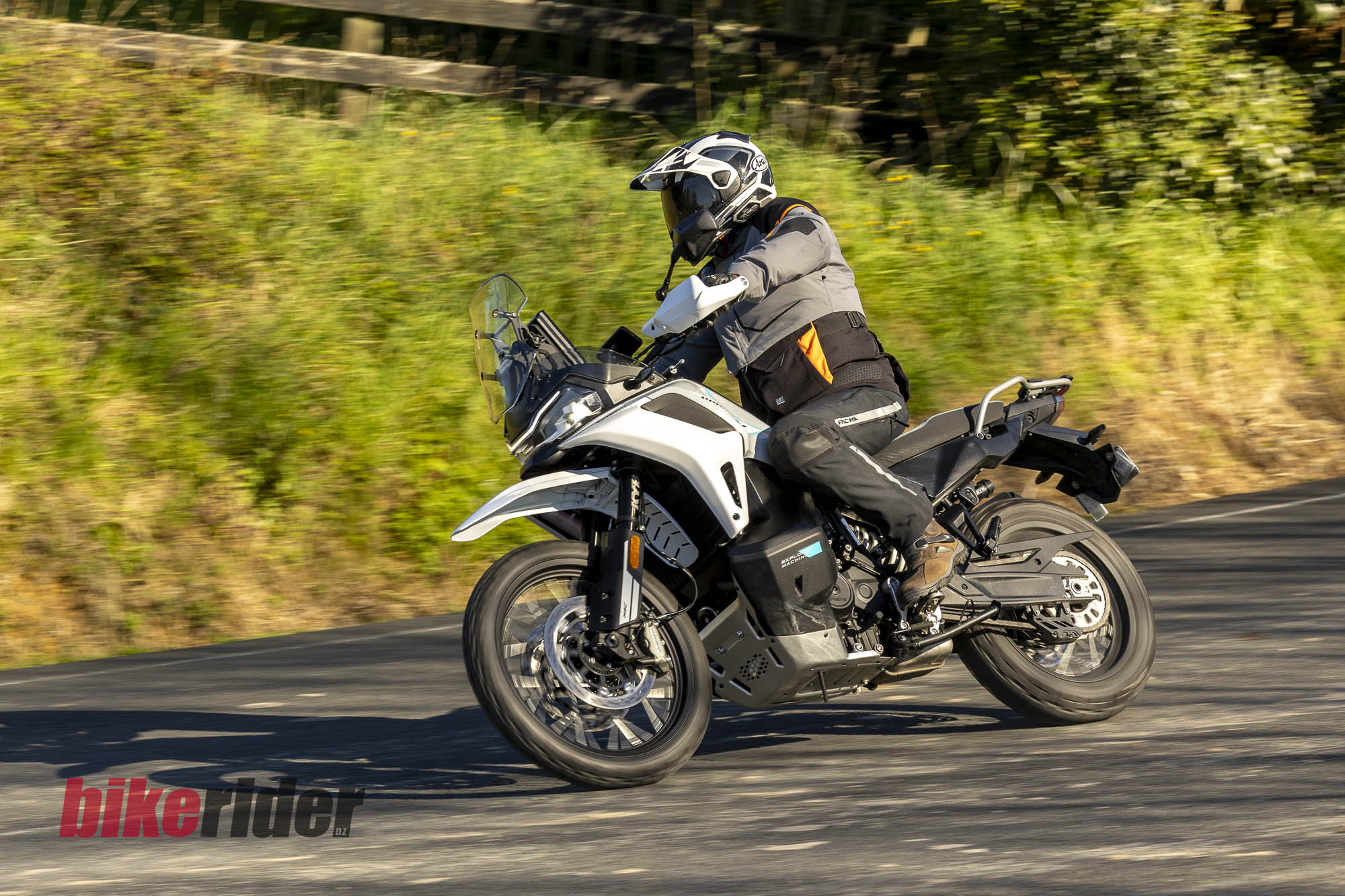 Rider on the CFMOTO 1000MT-X adventure bike viewed from the front quarter on a sealed back road