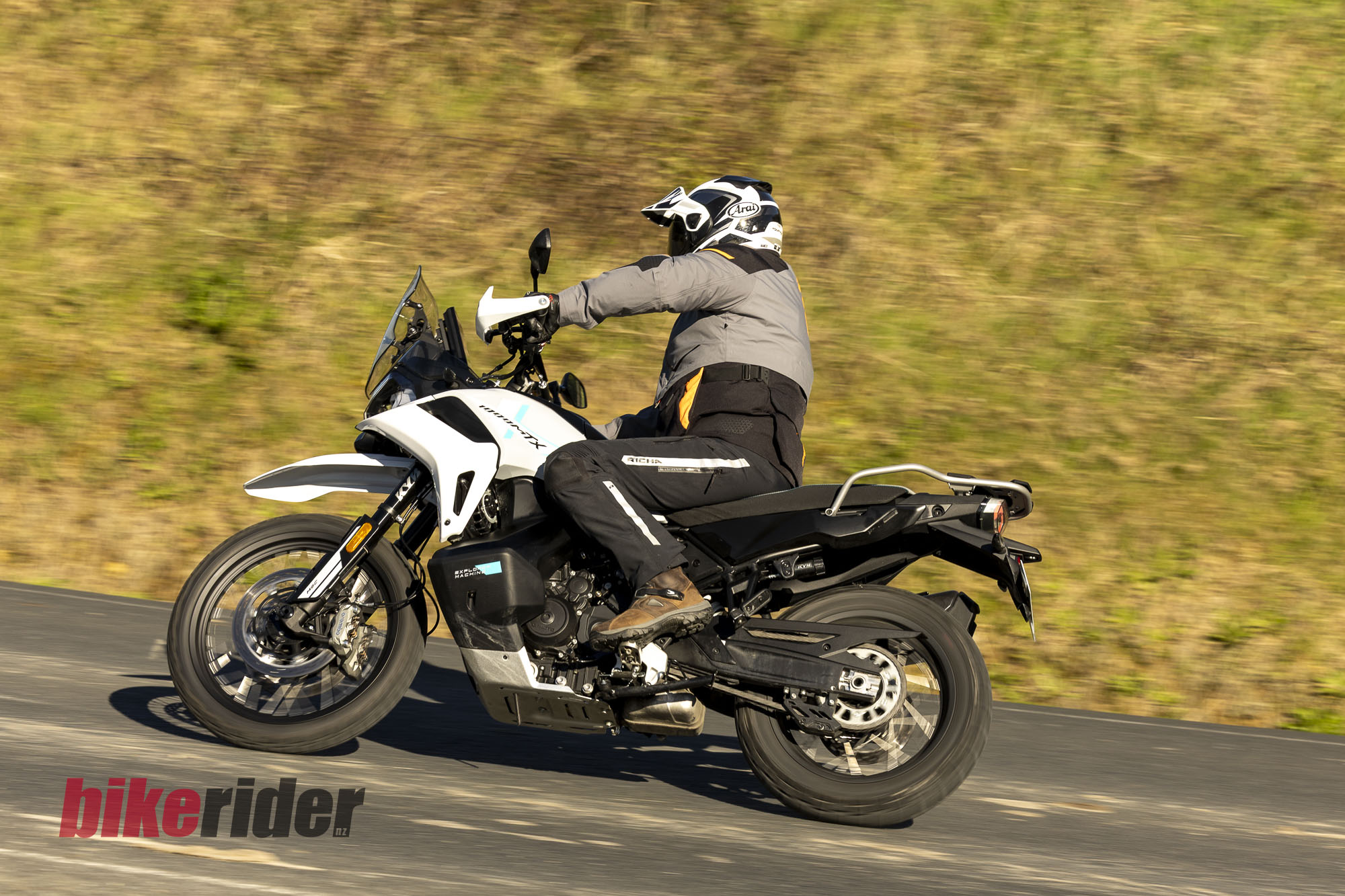 CFMOTO 1000MT-X adventure bike ridden along a sealed road, viewed from the rear quarter